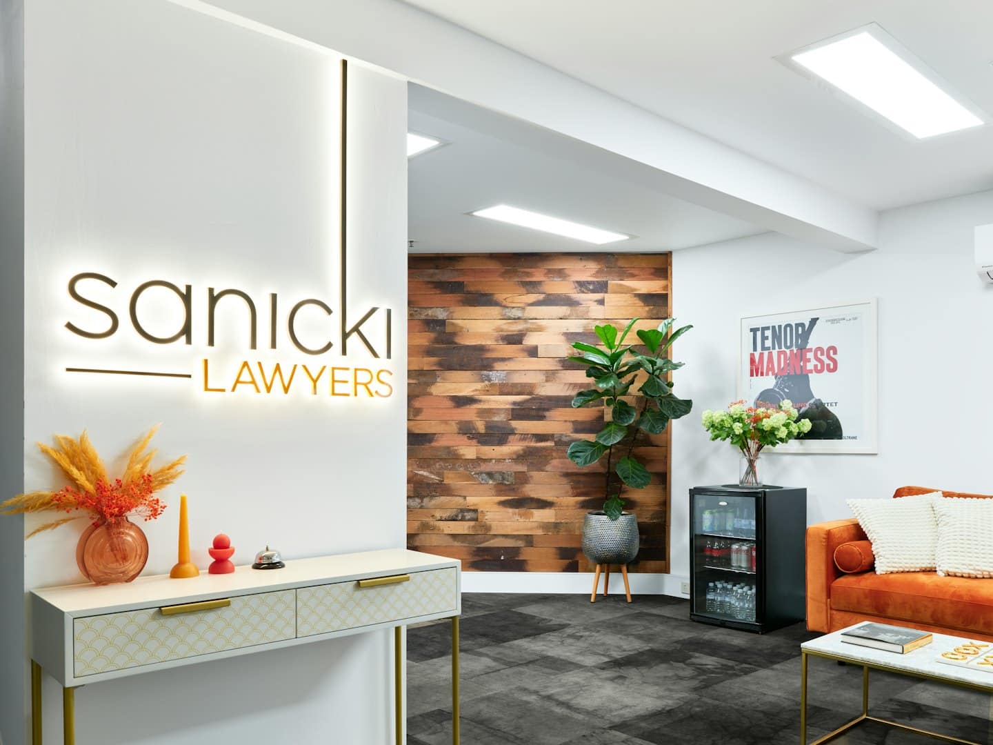 Nowoczesna recepcja biurowa z sofą i szyldem Sanicki Lawyers.